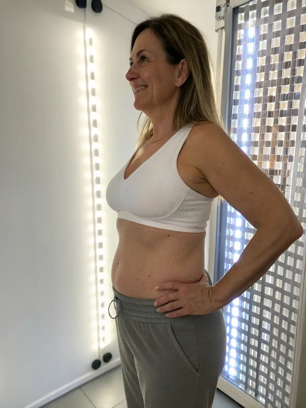 A patient showing a flat and toned abdomen after a Tummy Tuck procedure at Iboma Center, photographed in a luxurious, comfortable setting in Miami.